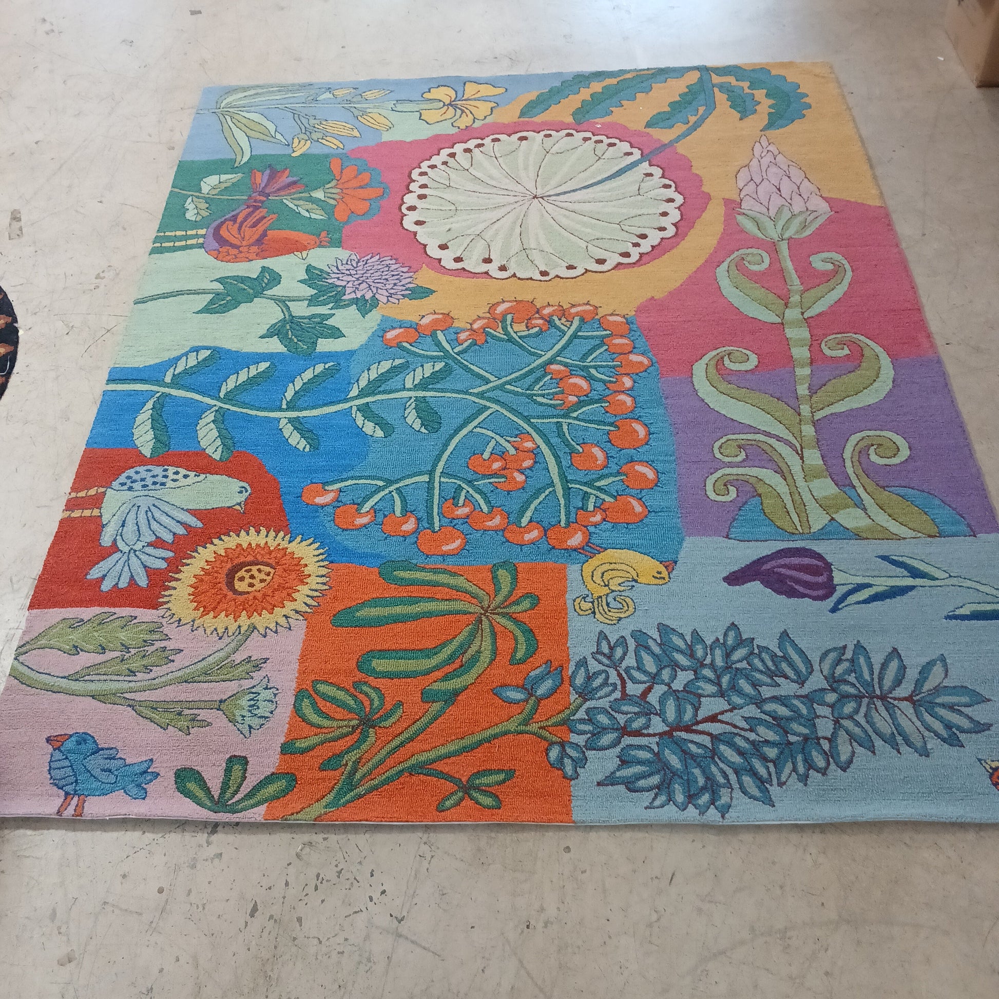 Colorful floral and nature-themed fabric on a concrete floor